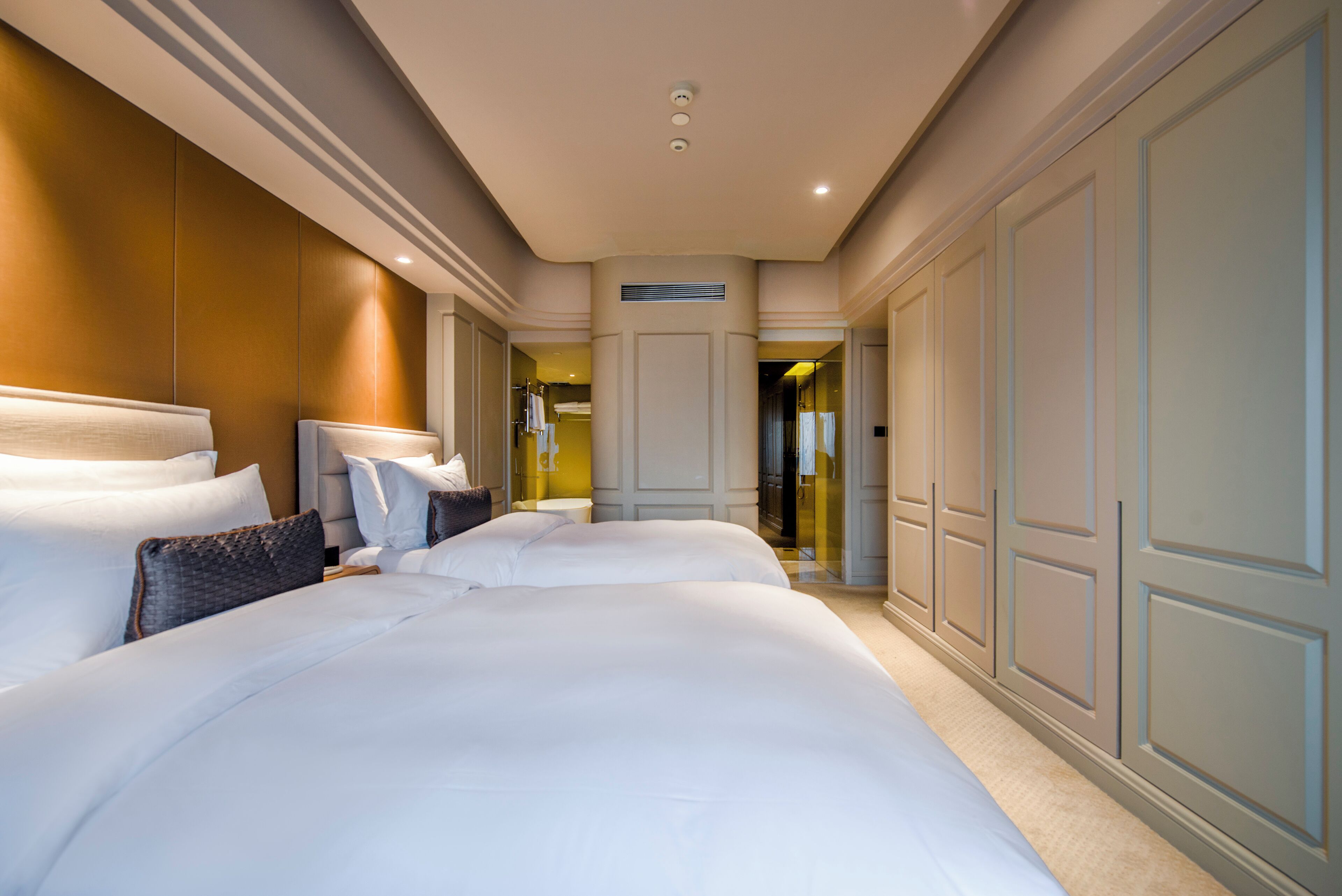 A hotel room with a large bed, a wardrobe, and a bathroom visible through an open door.