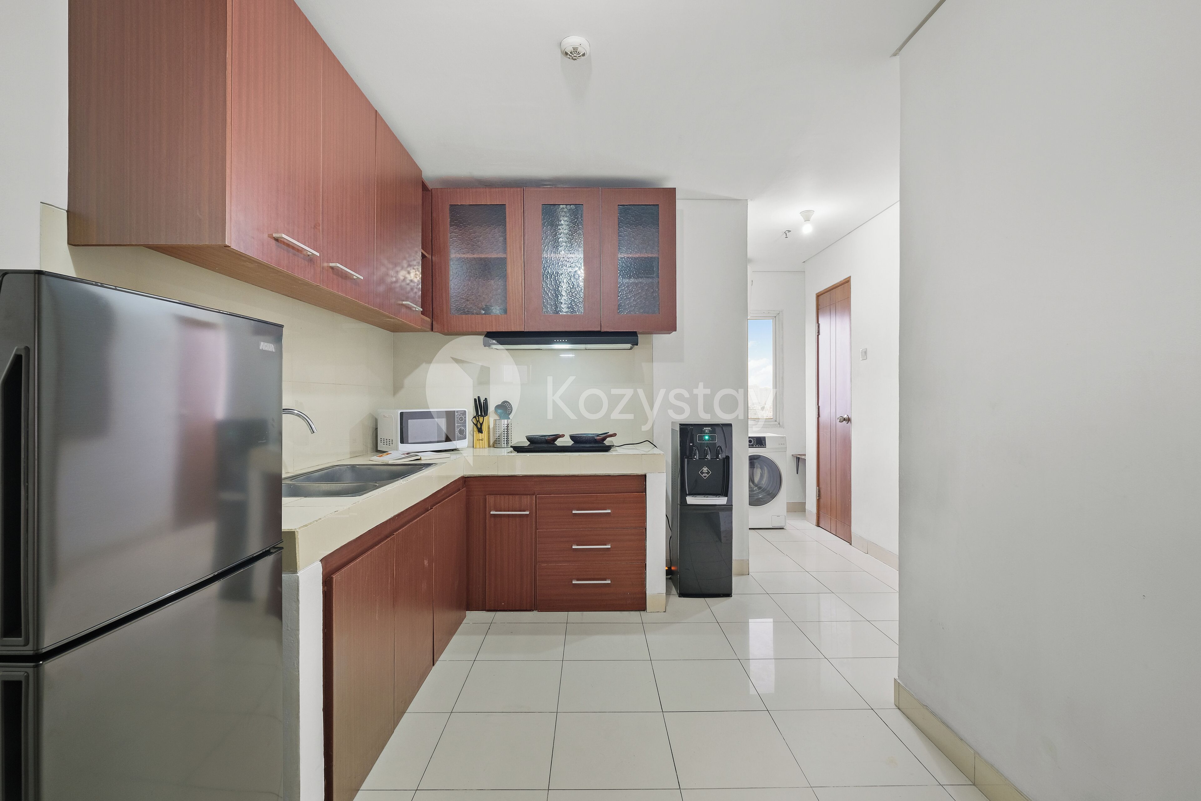 A modern kitchen with stainless steel appliances, wooden cabinets, and a tiled floor.
