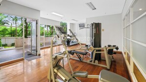 Un gimnasio moderno con máquinas de cardio, estaciones de pesas y una pantalla de televisión.