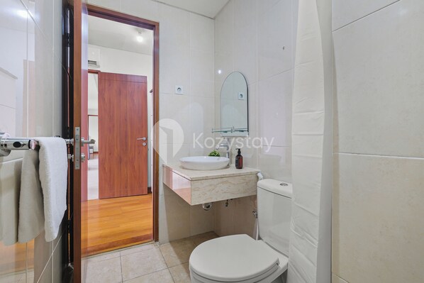 A modern bathroom with a white toilet, a marble sink, and a wooden door.