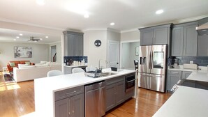 A modern kitchen with grey cabinets, stainless steel appliances, and a central island.