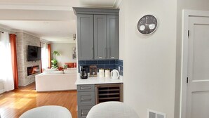 A modern kitchen with grey cabinets, a white countertop, and a built-in stove. There is a clock on the wall and a door to the right.