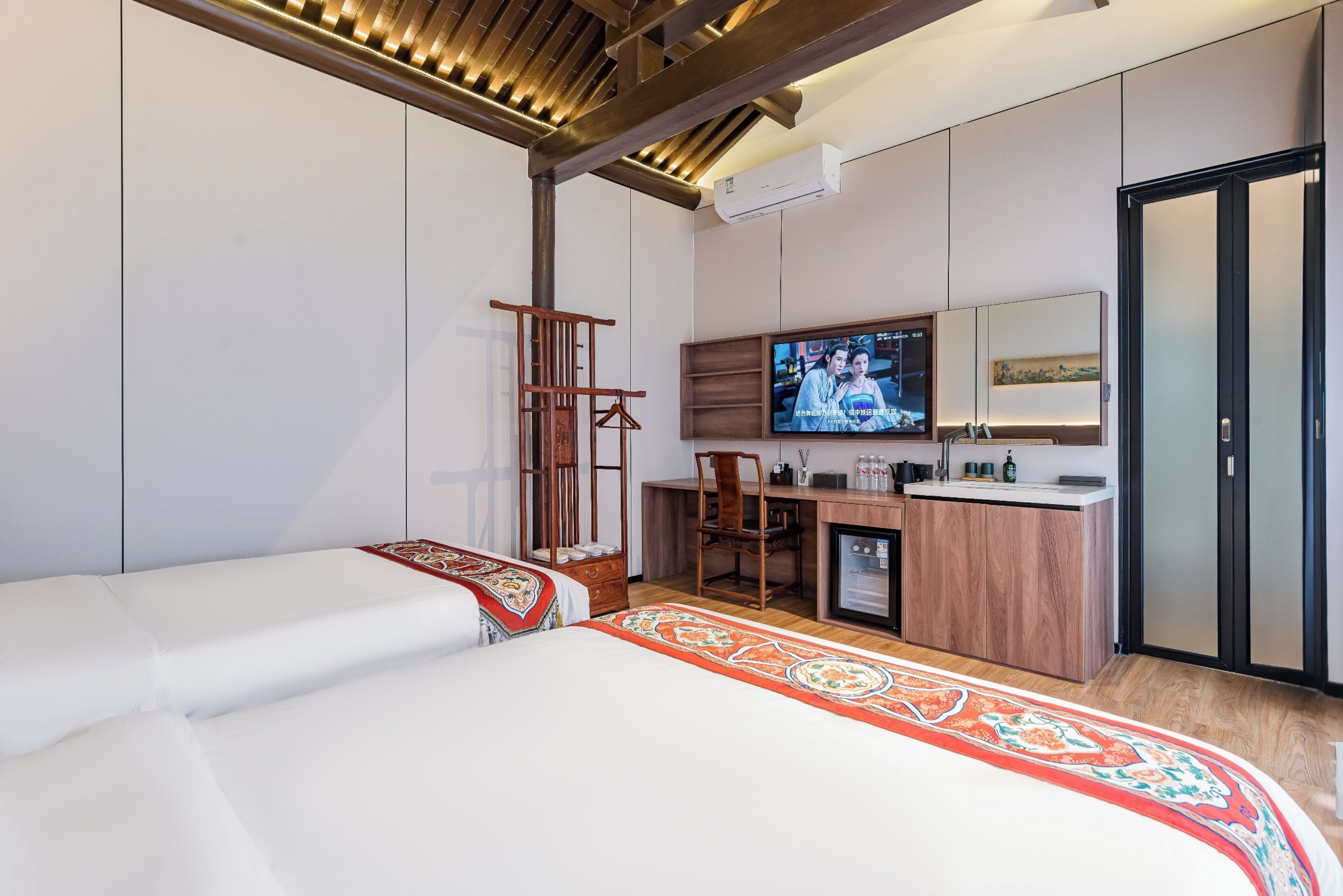 Een moderne hotelkamer met een bed, bureau en televisie.