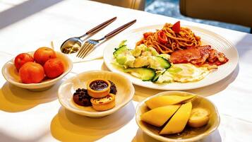 A table with plates of food including spaghetti, salad, and fruit.
