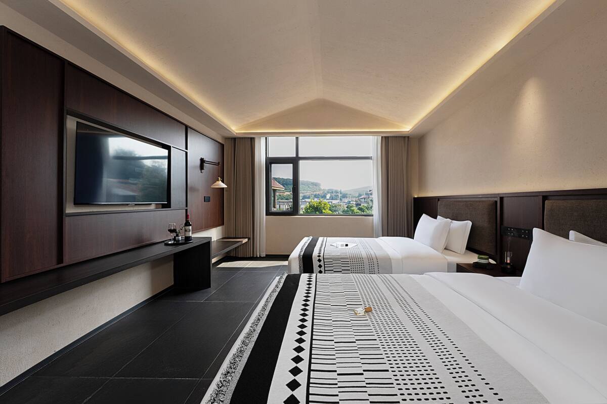 Ein modernes Hotelzimmer mit einem großen Bett, einem Fernseher und einem Fenster mit Blick auf die Stadt.