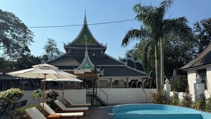 A traditional building with a green roof and white walls, a swimming pool, and lounge chairs. - Jinghong Chen Duo Nan Shan Man Zhen (Xishuangbanna Dai)