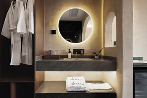 A modern bathroom with a round mirror, dark countertops, and neatly folded towels. - Jinghong Chen Duo Nan Shan Man Zhen (Xishuangbanna Dai)