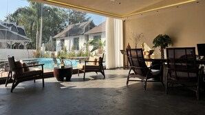 A spacious indoor area with a pool, comfortable seating, and a view of traditional houses. - Jinghong Chen Duo Nan Shan Man Zhen (Xishuangbanna Dai)