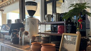 A coffee shop counter with a coffee machine, jars of coffee beans, and terracotta pots. - Jinghong Chen Duo Nan Shan Man Zhen (Xishuangbanna Dai)