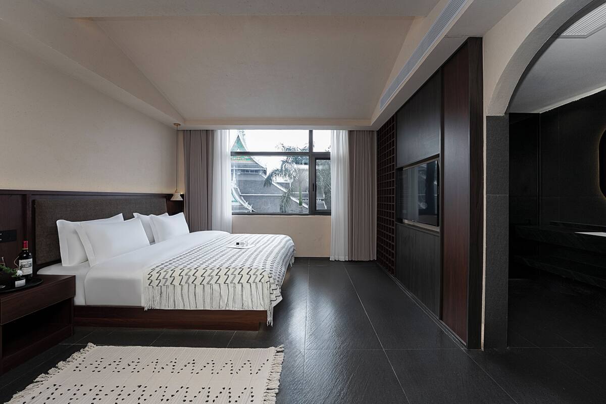 Ein modernes Hotelzimmer mit einem großen Bett, Blick auf die Stadt und dunklen Holzvertäfelungen.