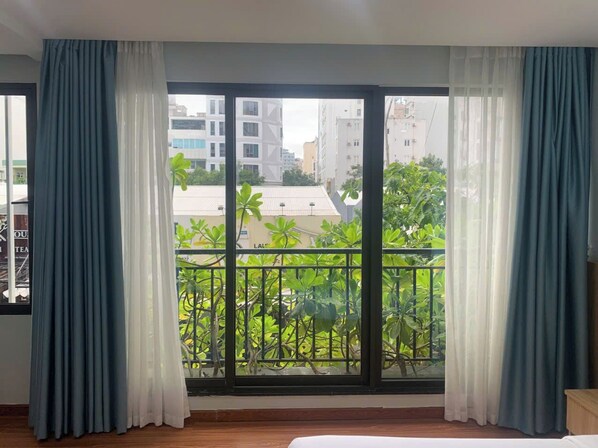 A room with a large window, a bed, and curtains.
