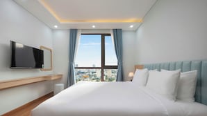Ein Hotelzimmer mit einem großen Bett, einem an der Wand montierten Fernseher und Blick auf die Stadt durch das Fenster.