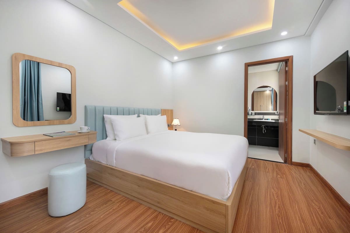 Ein modernes Schlafzimmer mit einem hölzernen Bett, einem Nachttisch, einem Spiegel und einem kleinen Hocker.