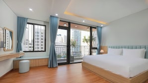 Ein modernes Hotelzimmer mit einem großen Bett, einer Bank, einem kleinen Hocker, einem Spiegel und einem Fenster mit Vorhängen.