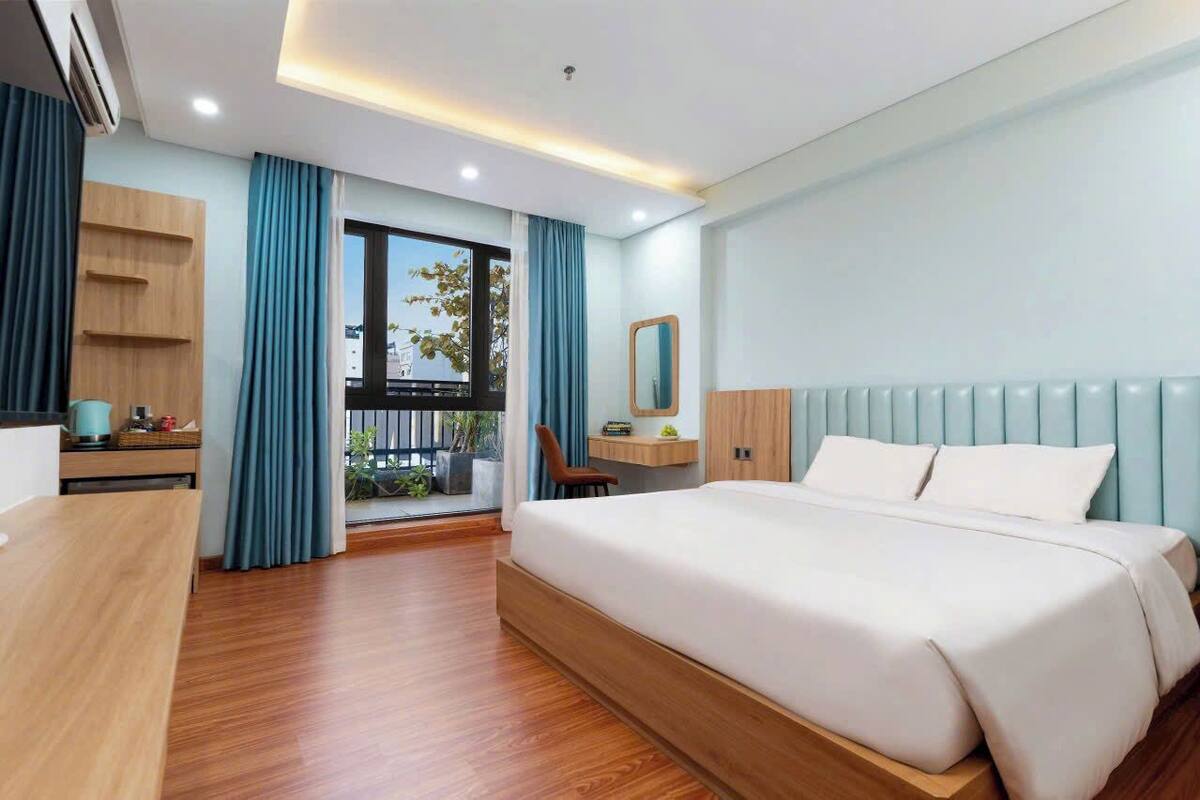 Ein modernes Hotelzimmer mit einem großen Bett, einem Schreibtisch, einem Stuhl und einem fenster mit Vorhängen.