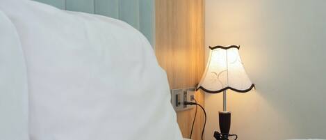 A bed with white sheets, a bedside lamp, and a wooden headboard.