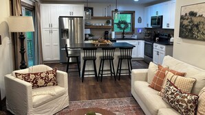 Una cocina moderna con una isla central, armarios blancos y electrodomésticos de acero inoxidable.