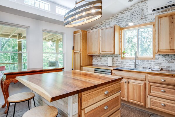 Une cuisine moderne avec des meubles en bois, un grand îlot central et un luminaire suspendu.
