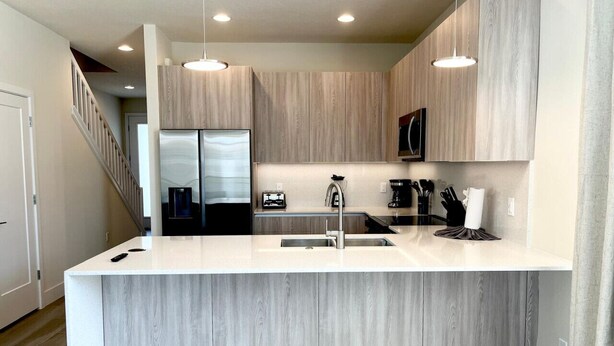 A modern kitchen with a large island, stainless steel appliances, and wooden cabinetry.