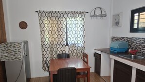 A compact kitchen with a dining table, chairs, a refrigerator, and a sink. - We are directly on the beach with 50 meters of frontage and beautiful sunsets (Bobon)