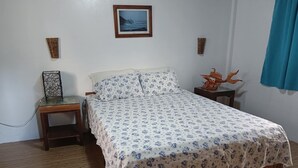 A bedroom with a wooden bed, a bedside table, a small desk, and a framed picture on the wall. - We are directly on the beach with 50 meters of frontage and beautiful sunsets (Bobon)