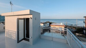 A modern balcony with a door, a small enclosed area, and a view of the sea. - The FLOW Okinawa (Chatan)
