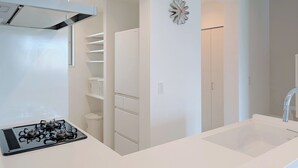 A modern kitchen with a gas stove, white cabinets, and a built-in oven. - The FLOW Okinawa (Chatan)
