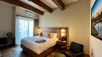 A hotel room with a large bed, bedside tables, a desk, and a chair.