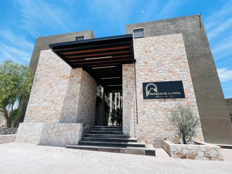 A stone building with a sign reading "Puertas de la Peña Hotel & Spa".
