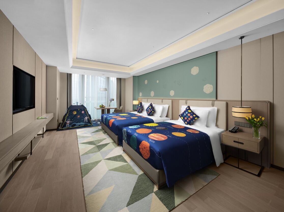A hotel room with two beds, a TV, a desk, and a chair.