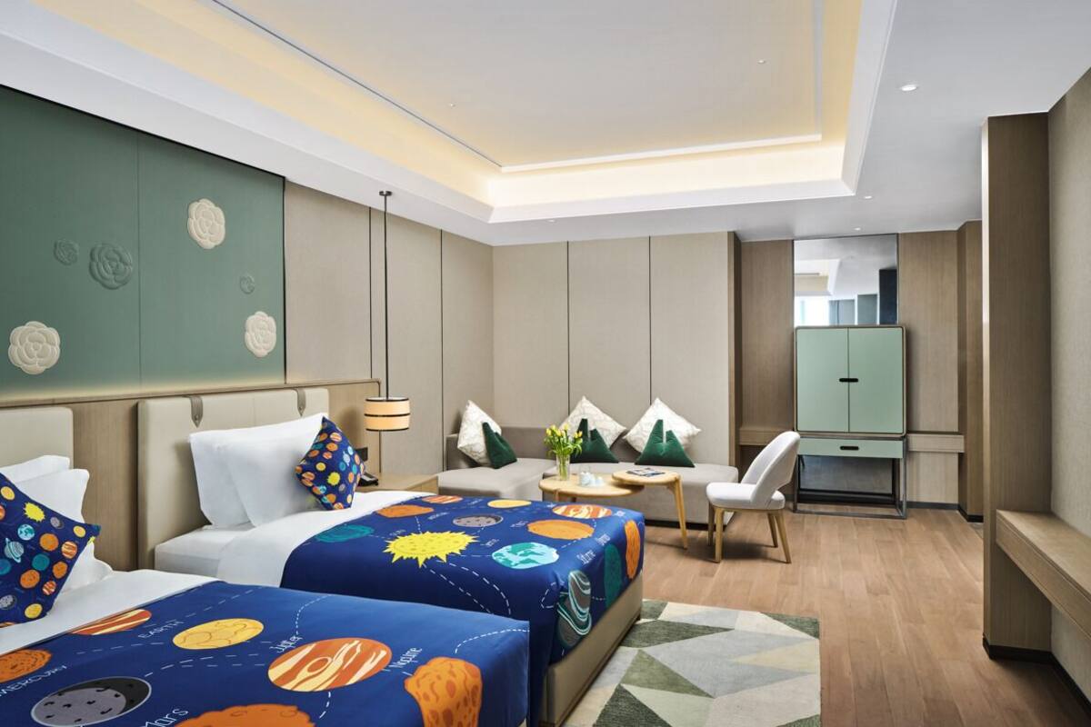 A hotel room with two beds, a sofa, a desk, and a cabinet.