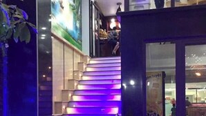 Una escalera iluminada con luces moradas que lleva a la entrada de un edificio.