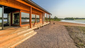 Una cabaña de madera con amplias ventanas que dan a un lago.