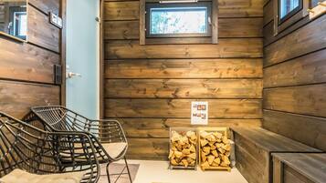 Een blokhutinterieur met houten wanden, een raam, een stoel, een bank en een stapelhout.