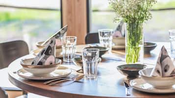 A round dining table set with plates, bowls, cutlery, and glasses, with a vase of flowers in the center.