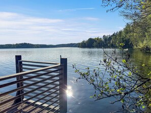 A wooden dock extending into calm water with a forested shoreline in the background.