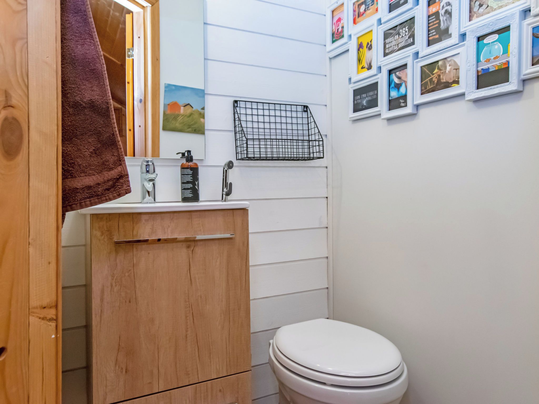 Un baño con tocador de madera, inodoro y lavamanos instalado en la pared.