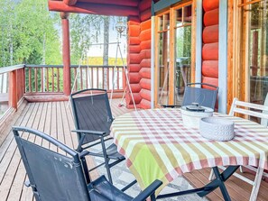 A wooden deck with a table and chairs, a lantern, and a view of trees. - Kiviranta by Interhome (Lahti)