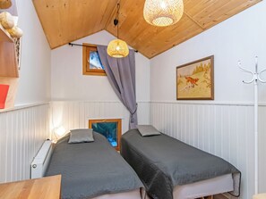 A room with two beds, a wooden ceiling, a painting, and a hanging light fixture. - Kiviranta by Interhome (Lahti)