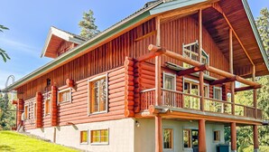 A log cabin with a large porch, multiple windows, and a steeply pitched roof.