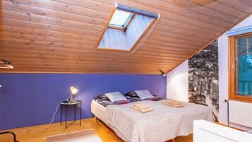 Ein Schlafzimmer mit Dachfenster, einem Bett mit Kissen, einer Nachttischlampe und einer Heizung.