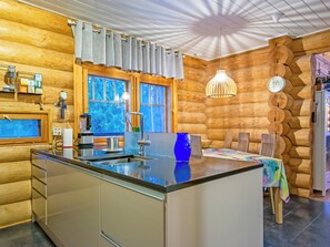 L’intérieur d’une cabane en rondins, avec un îlot de cuisine, des murs en bois et un coin repas.