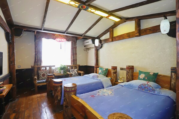 A traditional room with wooden beams, two beds with blue bedding, a wooden table, a chair, and a window with curtains. - Butterfly Loves Flower Inn (Zhangjiajie)