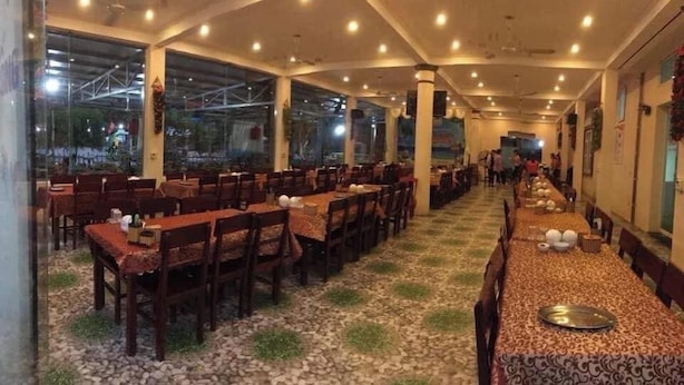 A restaurant with multiple tables and chairs, large windows, and a tiled floor.