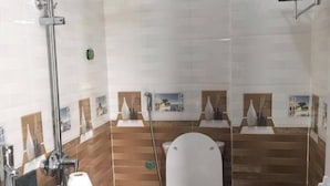 A bathroom with a sink, toilet, shower, and decorative tiles.