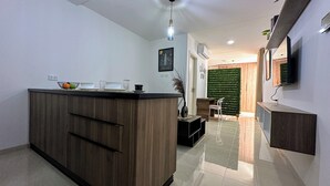 Una cocina moderna con una isla de madera, un comedor con pared verde y un televisor montado en la pared.