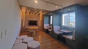 Un interior moderno con una pared de listones de madera, una mesa redonda con sillas y asientos integrados a lo largo de las paredes.