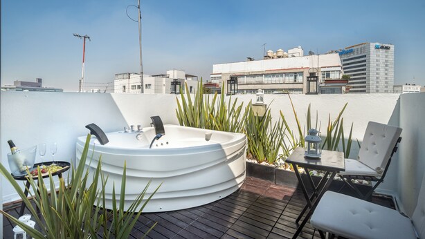 Terraza en la azotea con jacuzzi, zona de estar y vistas a la ciudad.