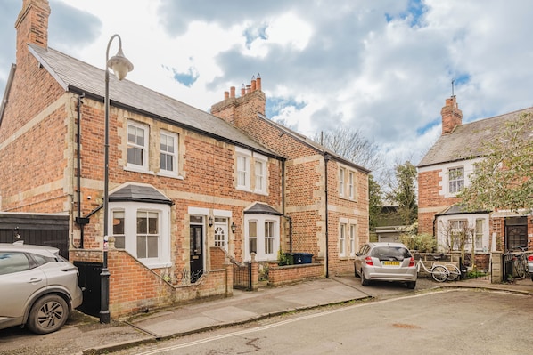 A residential street with brick houses, a parked car, and a bicycle. - Stunning 3 Bedroom Oxford Retreat (Oxford)