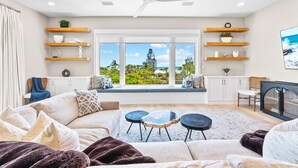 A modern living room with a large window, built-in shelves, a ceiling fan, and a cozy seating area. - 400ft to Beach, Ocean View, Pool, Rooftop, in the Siesta Key Village, 6-bdr (Siesta Key)